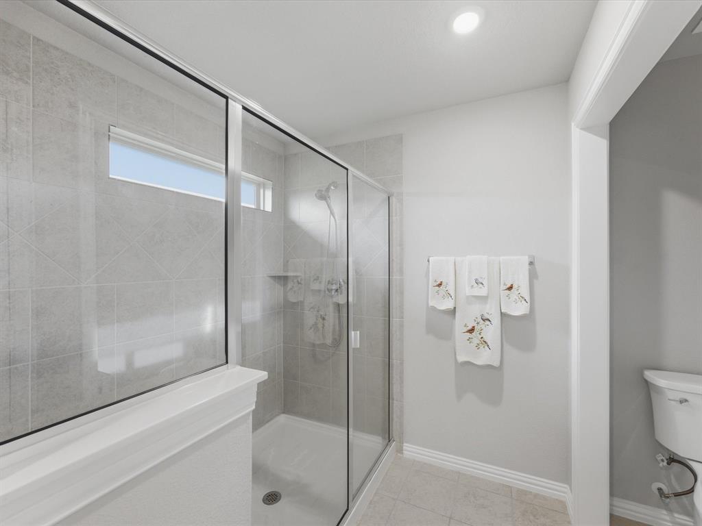 129 Springwood Ranch Loop Springtown, TX 76082 - Photo 19 of 26 Walk-in shower featuring glass enclosure, tiled walls, built-in shelving, a shower head, and an overhead lighting fixture