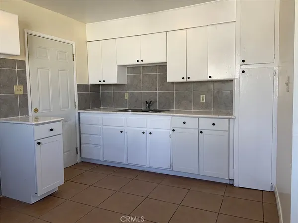 a kitchen with white cabinets and sink