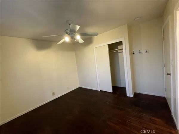 an empty room with wooden floor and fan