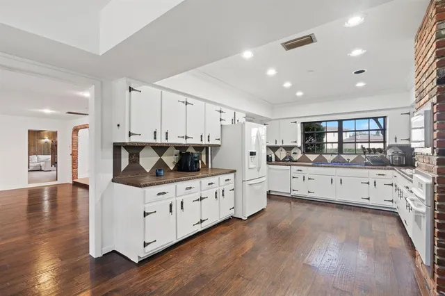 a kitchen with stainless steel appliances kitchen island granite countertop a stove top oven a sink dishwasher and cabinets with wooden floor