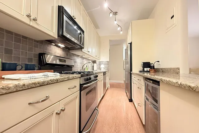 a kitchen with stainless steel appliances granite countertop a stove a sink and a refrigerator