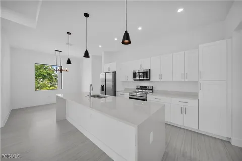 a kitchen with stainless steel appliances a stove a sink a refrigerator a center island and a window