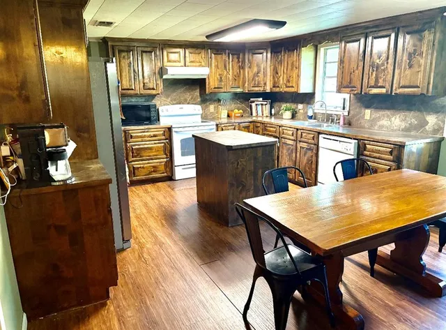 a kitchen with stainless steel appliances granite countertop table chairs sink and cabinets