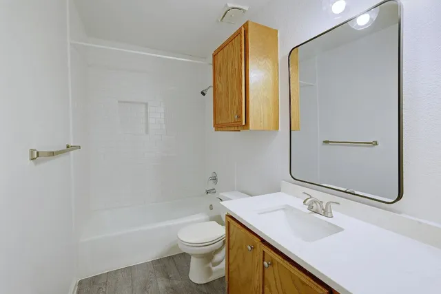 an empty room with wooden floor chandelier fan and windows