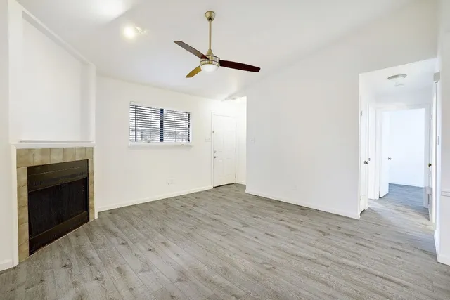 an empty room with wooden floor a ceiling fan and windows