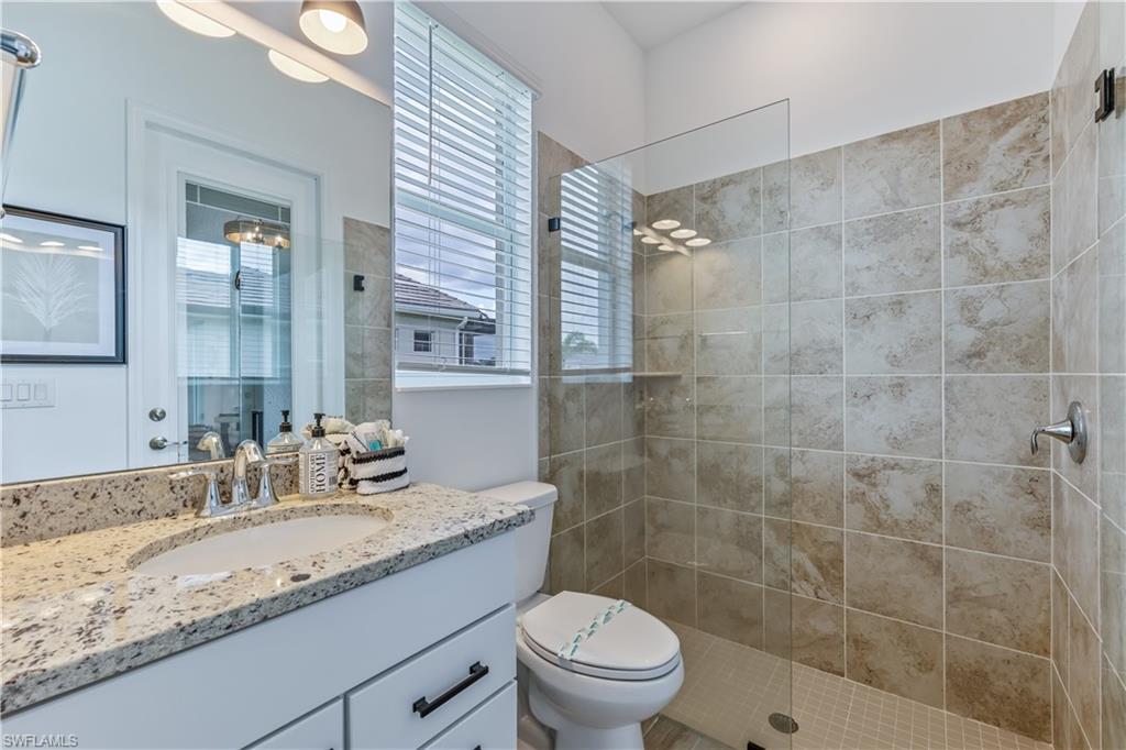 15977 Cranes Marsh Court Babcock Ranch, FL 33982 - Photo 20 of 24 a bathroom with a granite countertop sink a toilet a mirror and shower