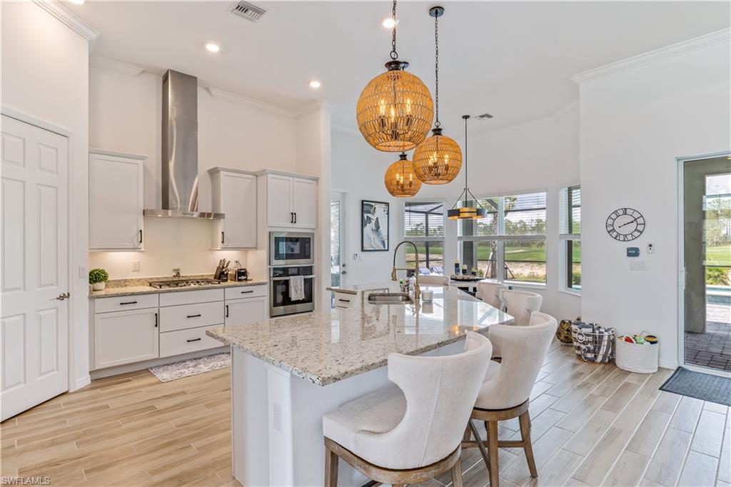 15977 Cranes Marsh Court Babcock Ranch, FL 33982 - Photo 8 of 24 a kitchen with stainless steel appliances granite countertop a stove a sink a dining table and chairs with wooden floor
