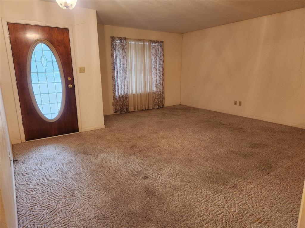 2821 Mccarley Drive Commerce, TX 75428 - Photo 15 of 32 an empty room with a fireplace and a chandelier