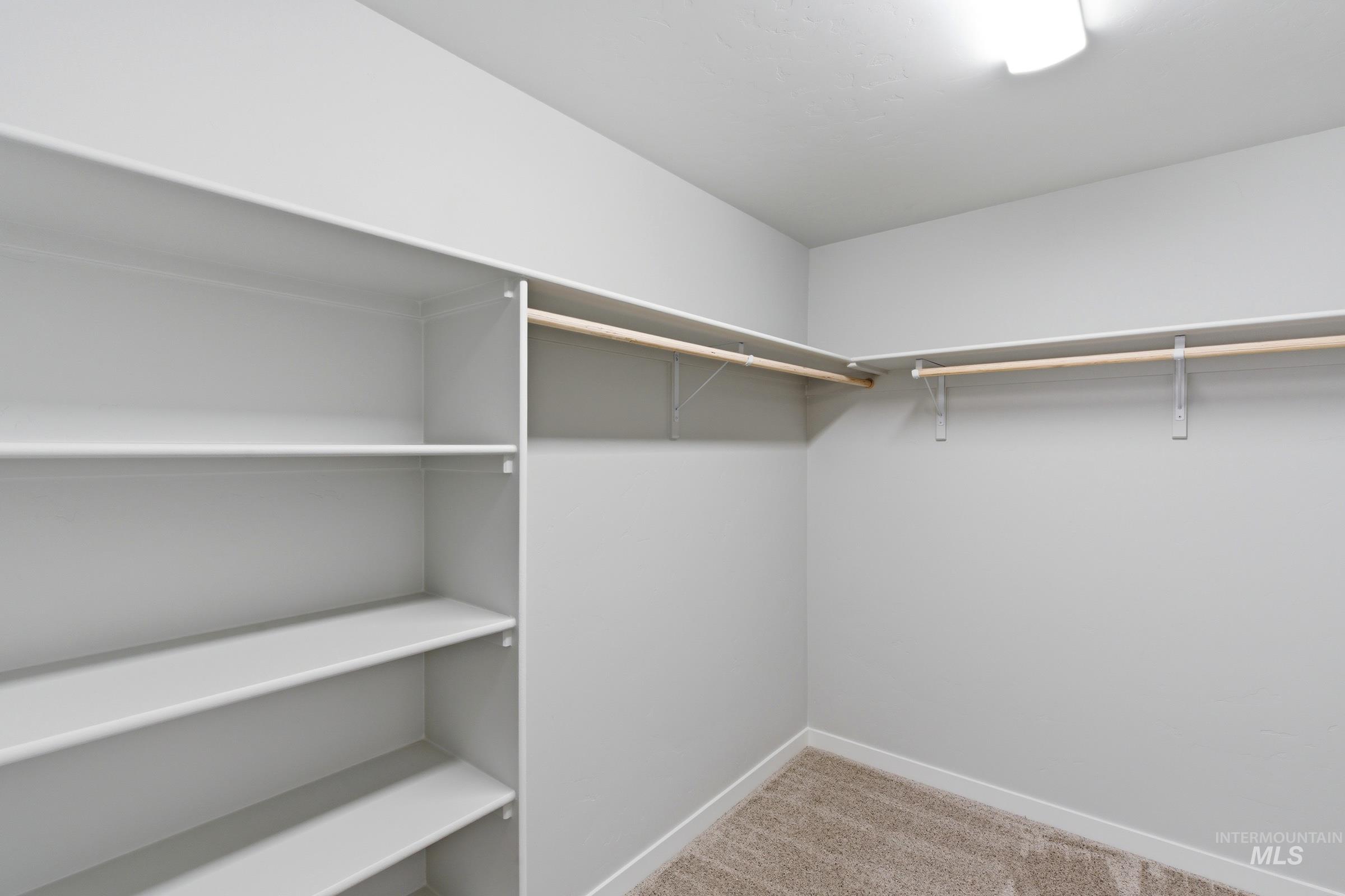 16558 Dunning Way Caldwell, ID 83607 - Photo 26 of 35 Spacious walk-in closet featuring extensive built-in shelving, multiple clothing rods, light-colored walls, and neutral carpeting