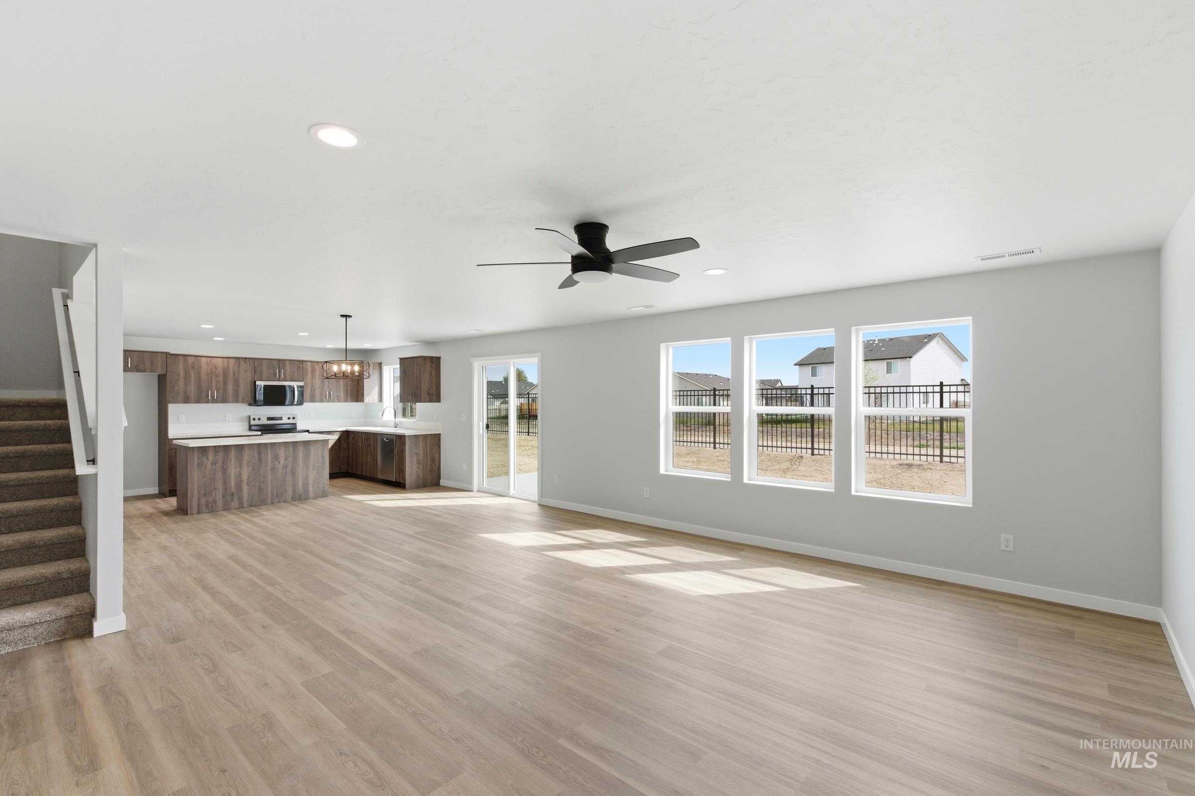 16558 Dunning Way Caldwell, ID 83607 - Photo 9 of 35 Open-concept living area featuring wood-finish flooring, a contemporary ceiling fan, and three large windows