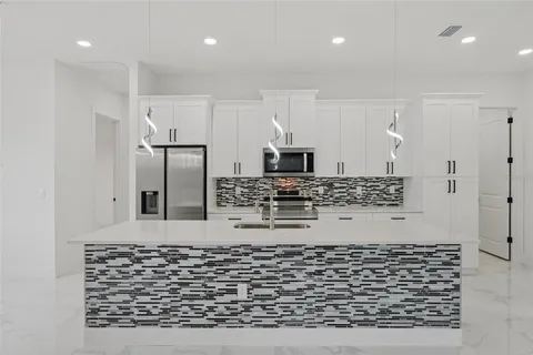 a kitchen with kitchen island a counter top space a refrigerator and cabinets