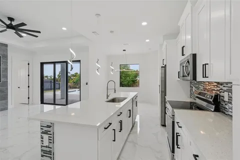 a large white kitchen with a large window and stainless steel appliances