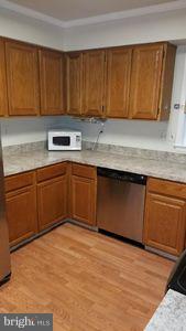 6249 Light Point Place Columbia, MD 21045 - Photo 8 of 18 a kitchen with stainless steel appliances granite countertop a sink dishwasher stove and cabinets with wooden floor