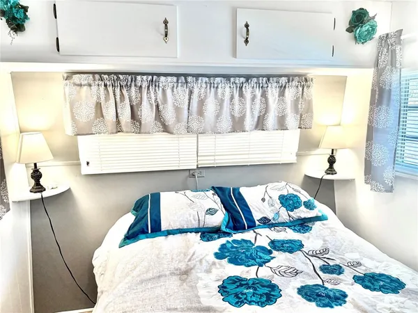 a bed sitting in a bedroom next to a window with wooden floor