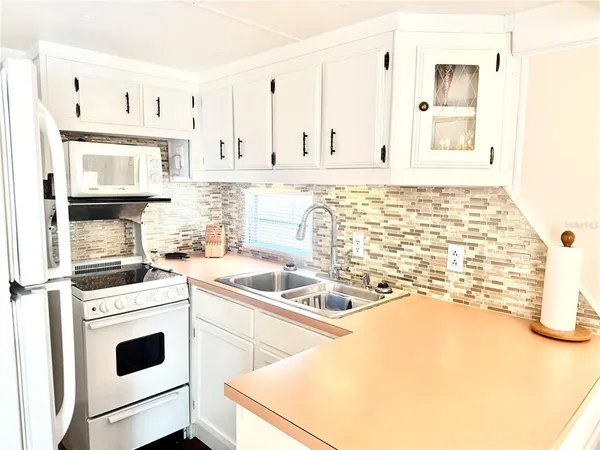a kitchen with stainless steel appliances a stove a sink and white cabinets
