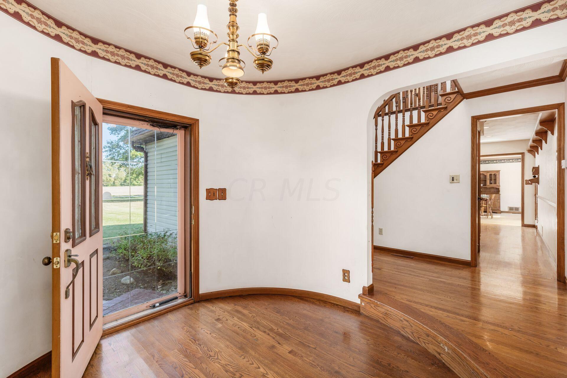 WELCOME INTO THIS UNIQUE HOME. ROUND FOYER WITH HARDWOOD FLOORING