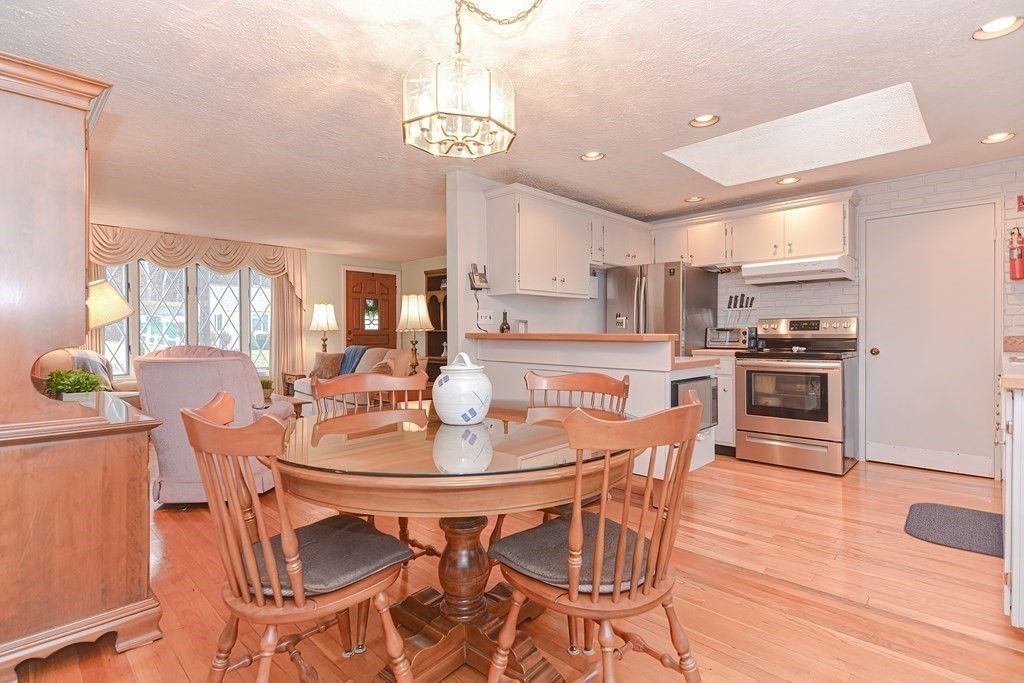 22 Grace Road Woburn, MA 01801 - Photo 4 of 36 a dining room with stainless steel appliances kitchen island granite countertop a table chairs and a refrigerator