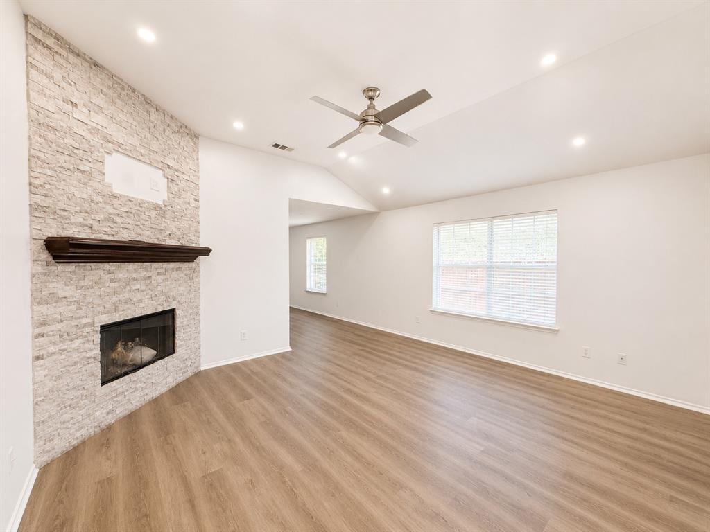 515 Haymarket Road Dallas, TX 75217 - Photo 2 of 15 Spacious living area featuring a stone-clad fireplace with a dark wood mantel, high vaulted ceilings, recessed lighting, wood-finish flooring, and a contemporary ceiling fan