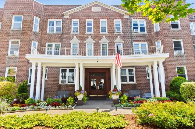 front view of a brick house with a yard and large trees