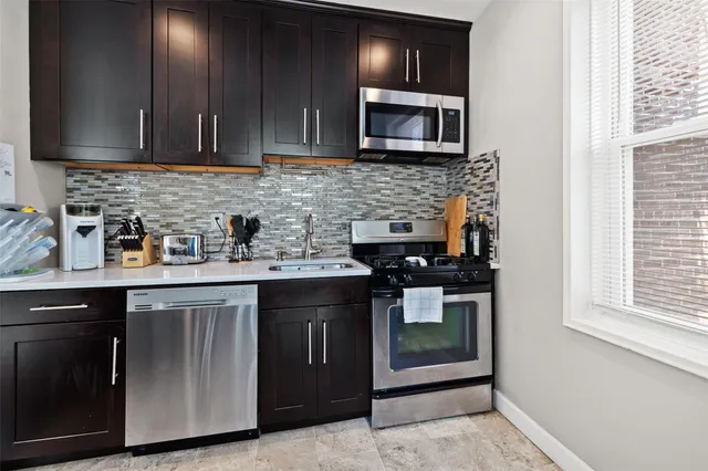 a kitchen with stainless steel appliances granite countertop a stove microwave and sink
