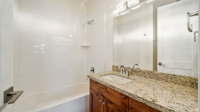 1238 Canyon View Road Midway, UT 84049 - Photo 26 of 36 Bathroom with a white tiled shower/tub combination, a wood-finish vanity, a light-toned stone countertop, and a large mirror with a multi-bulb light fixture