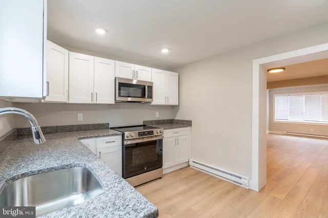 a kitchen with granite countertop a sink and a stove top oven with wooden floor