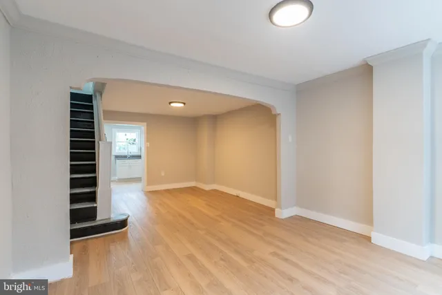 a view of an empty room with wooden floor and windows