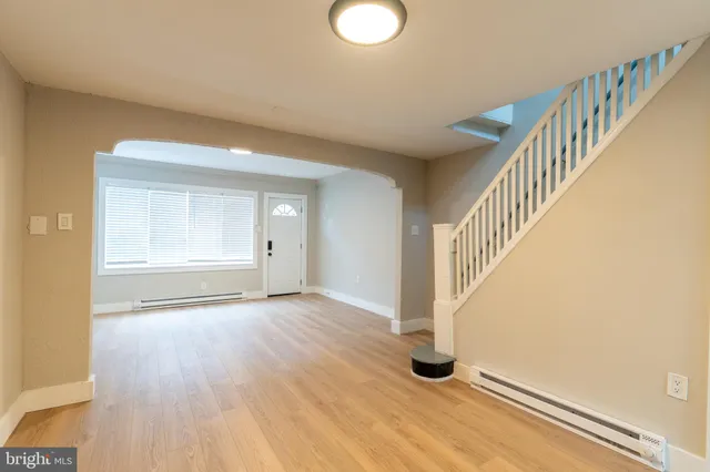 a view of an empty room with wooden floor and entryway