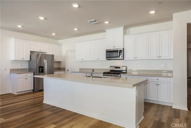 a kitchen with a sink a counter top space stainless steel appliances and cabinets