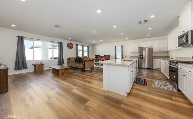 a living room with stainless steel appliances furniture and a kitchen view