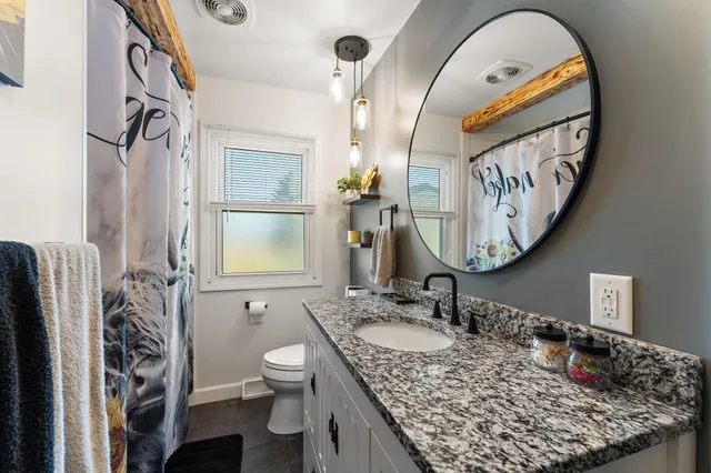 a bathroom with a granite countertop sink mirror vanity and a toilet