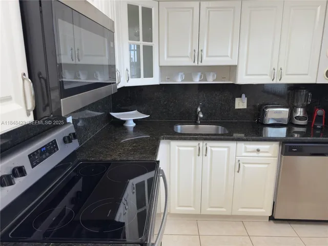 a kitchen with granite countertop white cabinets and black appliances