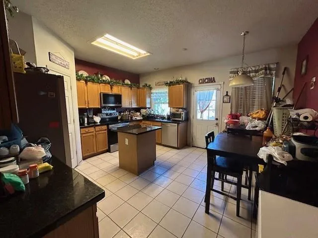 a kitchen with stainless steel appliances granite countertop a refrigerator a sink dishwasher a stove and a dining table with wooden floor