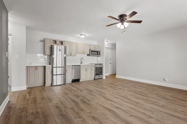 a view of a kitchen with wooden floor electronic appliances and a ceiling fan