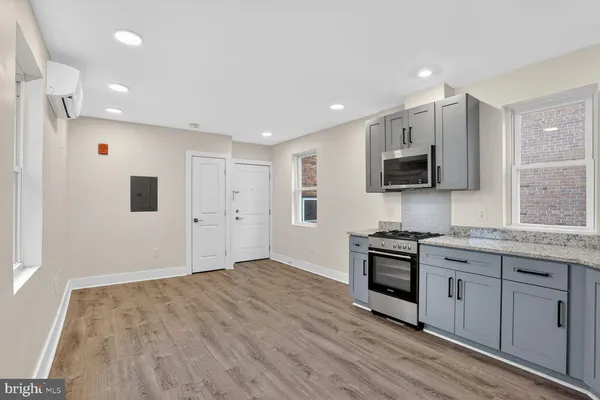 a kitchen with stainless steel appliances a stove top oven a sink a refrigerator white cabinets and wooden floor