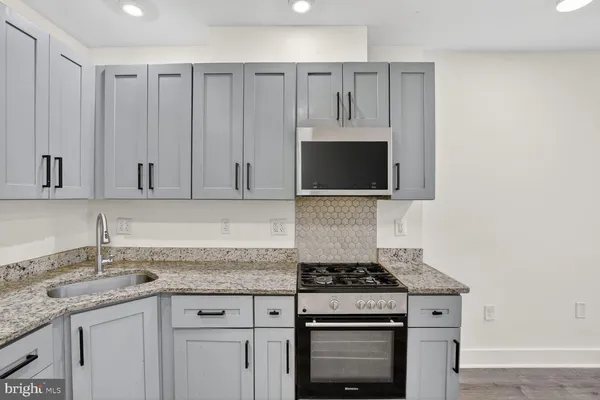 a kitchen with granite countertop a sink stove and cabinets