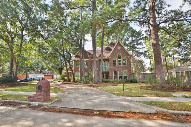 a front view of a building with trees and plants
