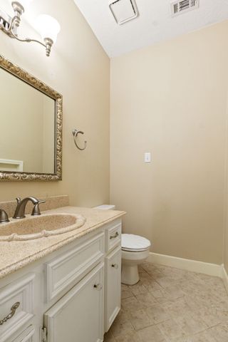 a bathroom with a granite countertop sink a toilet and a mirror