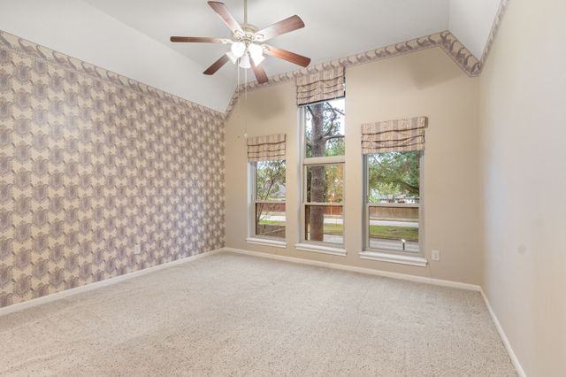 en empty room with windows and ceiling fan