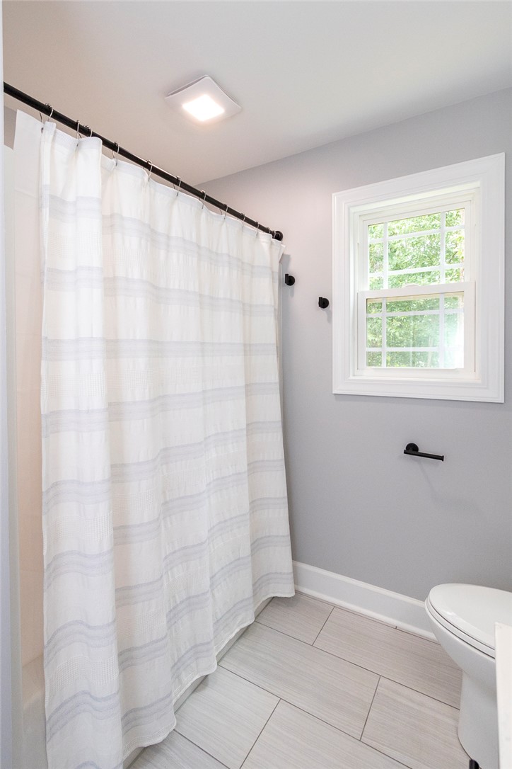 3080 McGee Road Iva, SC 29655 - Photo 24 of 49 A well-lit bathroom with tile flooring, featuring a practical shower curtain and ample natural light.