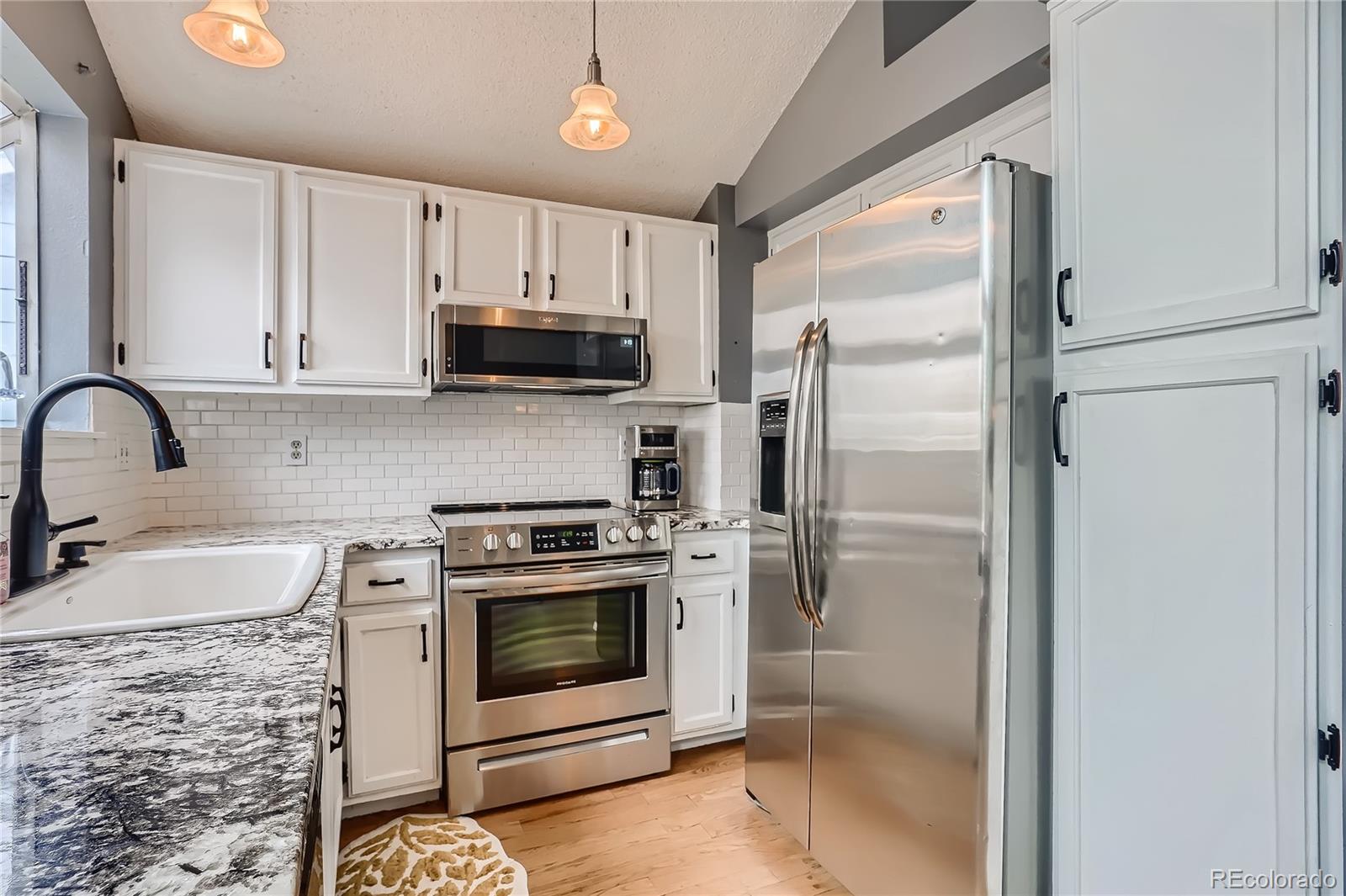 8994 Bermuda Run Circle Highlands Ranch, CO 80130 - Photo 7 of 30 a kitchen with a stove a sink and a refrigerator