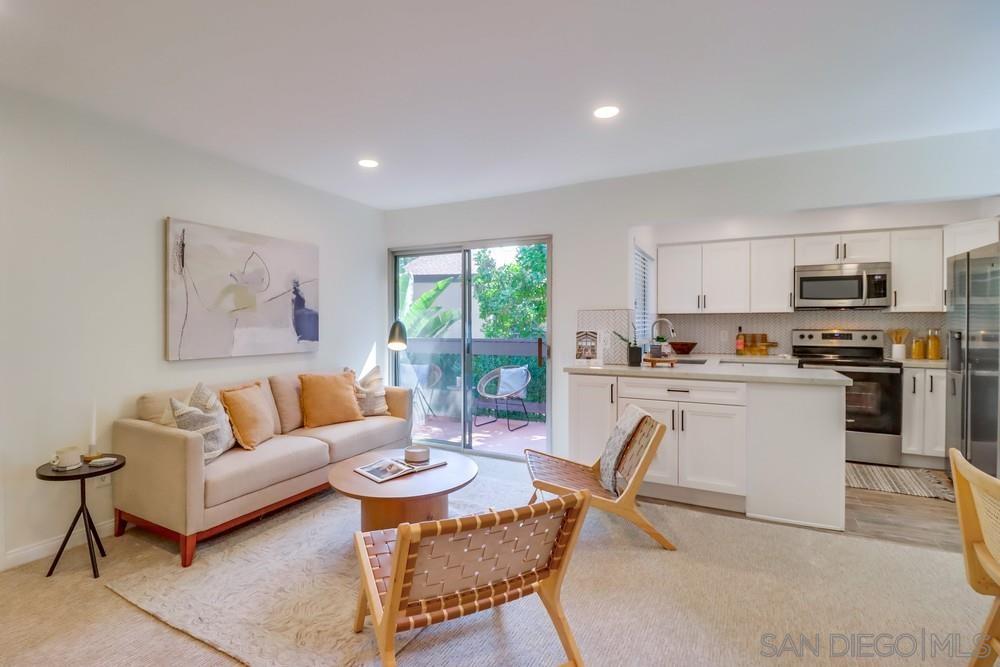 a living room with stainless steel appliances furniture and a kitchen view