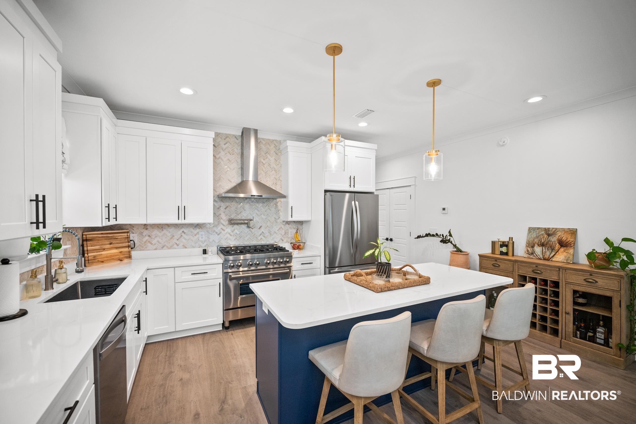 5501 Mobile Avenue Orange Beach, AL 36561 - Photo 8 of 40 Kitchen featuring appliances with stainless steel finishes, light wood-style flooring, decorative backsplash, wall chimney exhaust hood, and white cabinets