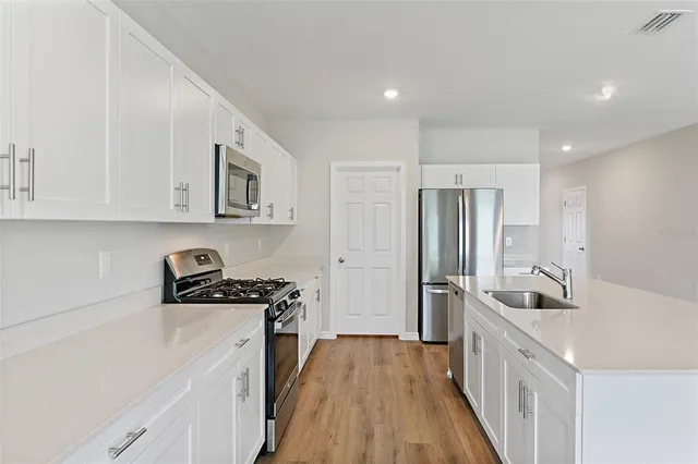 a kitchen with a sink a refrigerator and cabinets
