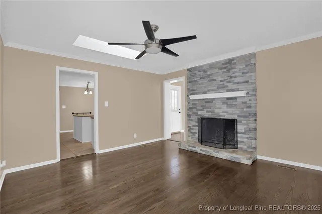 a view of a livingroom with a fireplace a ceiling fan and wooden floor