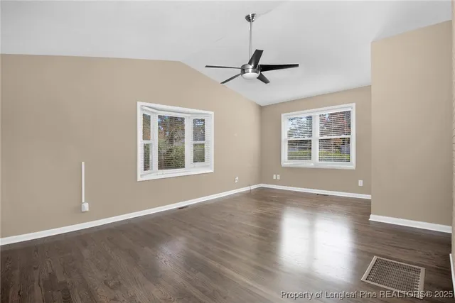 a view of an empty room with windows and wooden floor