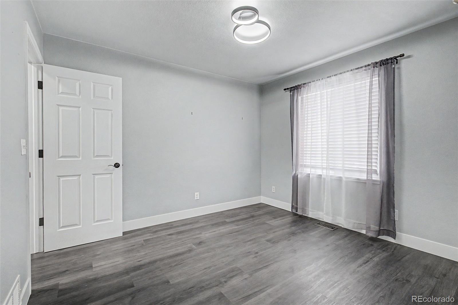 2233 70th Avenue Greeley, CO 80634 - Photo 15 of 50 an empty room with wooden floor and windows