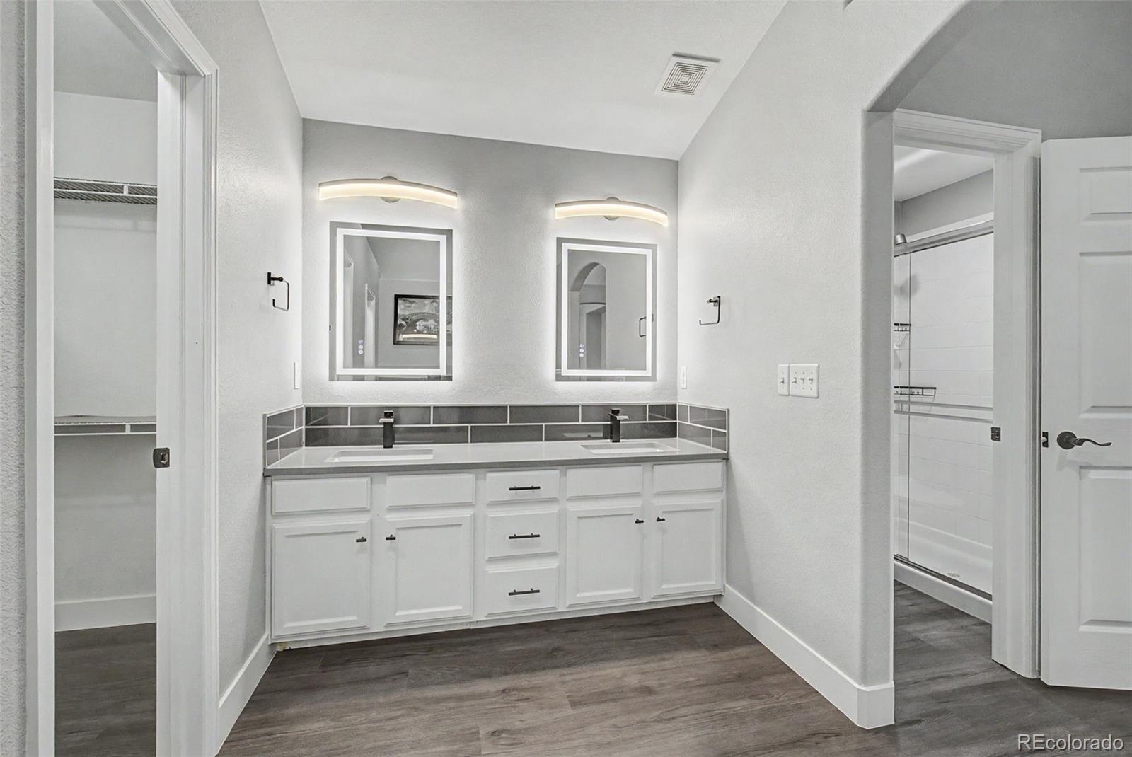 2233 70th Avenue Greeley, CO 80634 - Photo 23 of 50 a bathroom with a double vanity sink a mirror and a bathtub