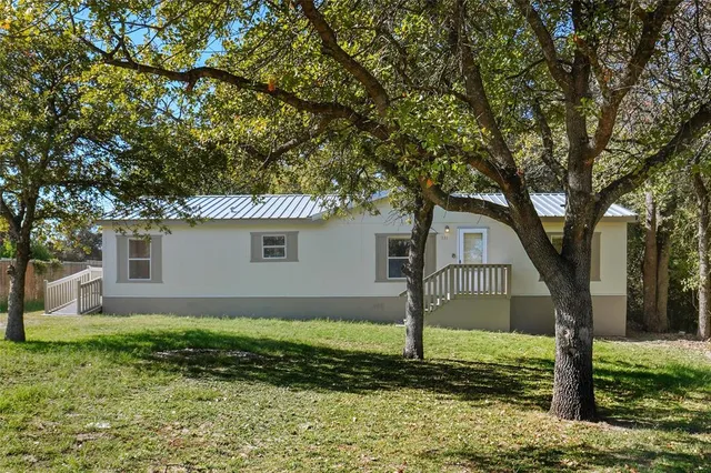 a view of a yard in front of a house with large tree