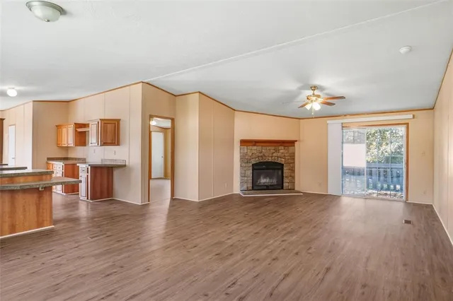 a view of an empty room with wooden floor and a fireplace